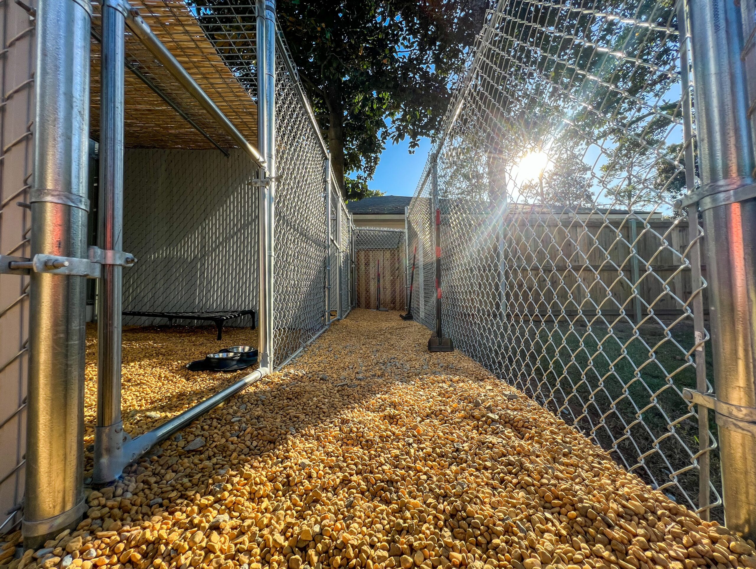 The sun shines brightly through a newly installed chain link fence.